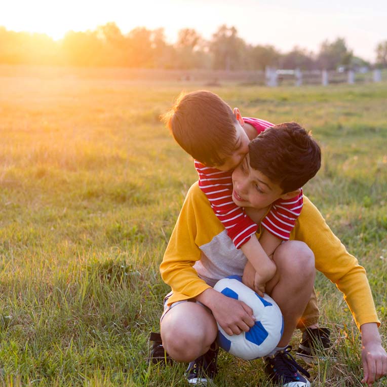 Two happy brothers playing soccer outside